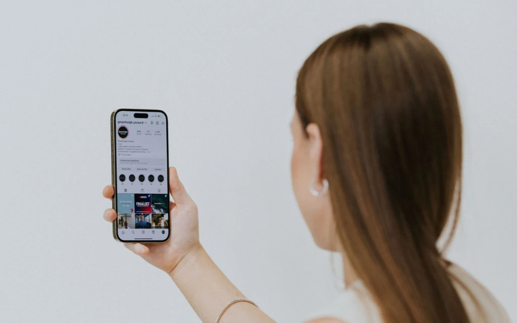 Back of woman's head while she looks at instagram on her phone